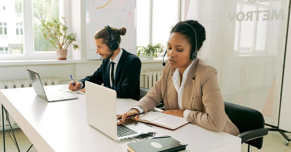 Professionnels de bureau avec casques, travaillant sur des ordinateurs portables, offrant un service client.