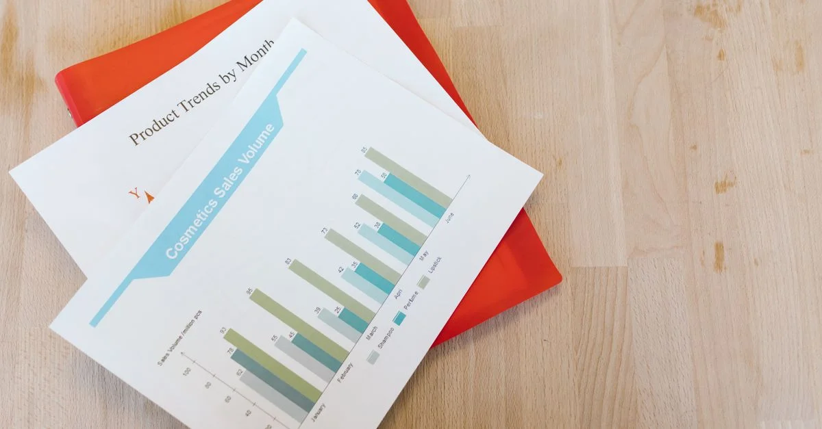 Vue de dessus d'un rapport de ventes de cosmétiques avec graphiques sur un bureau en bois.