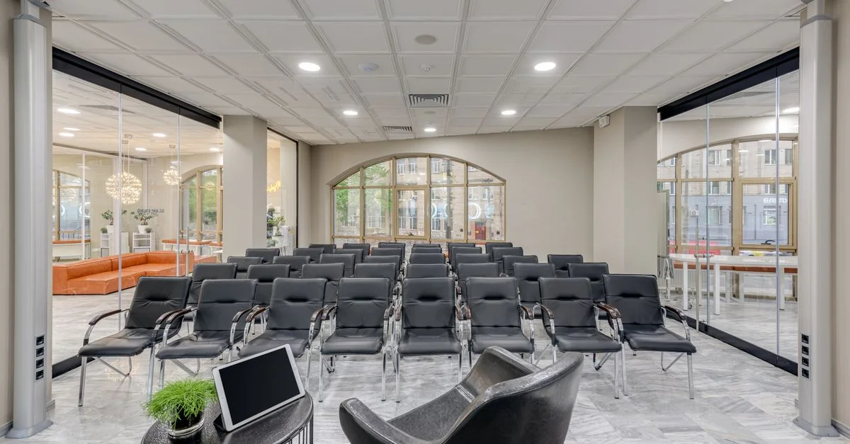 Salle de conférence spacieuse avec des sièges modernes et des murs en verre, idéale pour des réunions.
