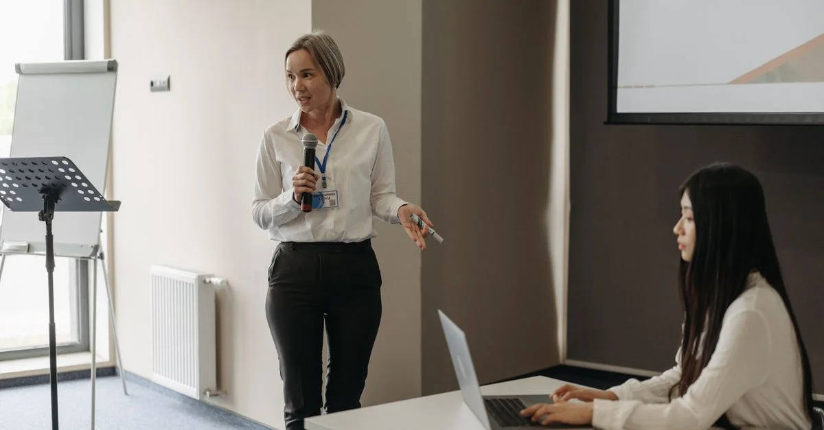 Deux femmes lors d'une réunion d'affaires avec une présentation et un ordinateur portable, favorisant une communication efficace.