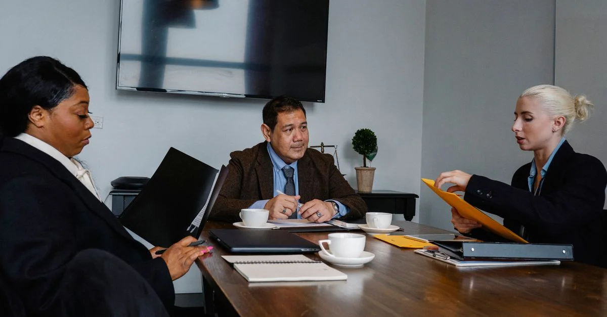 Une équipe d'affaires diversifiée discute de la stratégie dans une salle de réunion, collaborant sur des documents et du café.