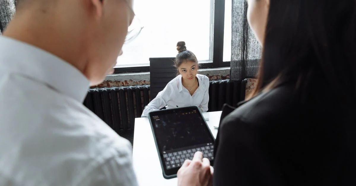 Professionnels discutant d'un projet autour d'une table avec une tablette, dans un cadre de bureau moderne.