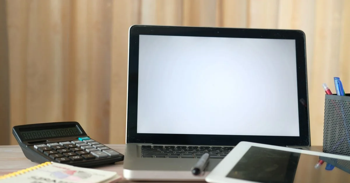 Bureau organisé avec un ordinateur portable, une calculatrice et une tablette prêtes pour des tâches professionnelles.