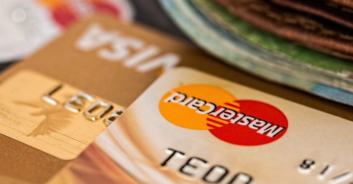 Gros plan de cartes de crédit avec les logos Visa et Mastercard à côté d'un portefeuille, idéal pour des thèmes financiers.