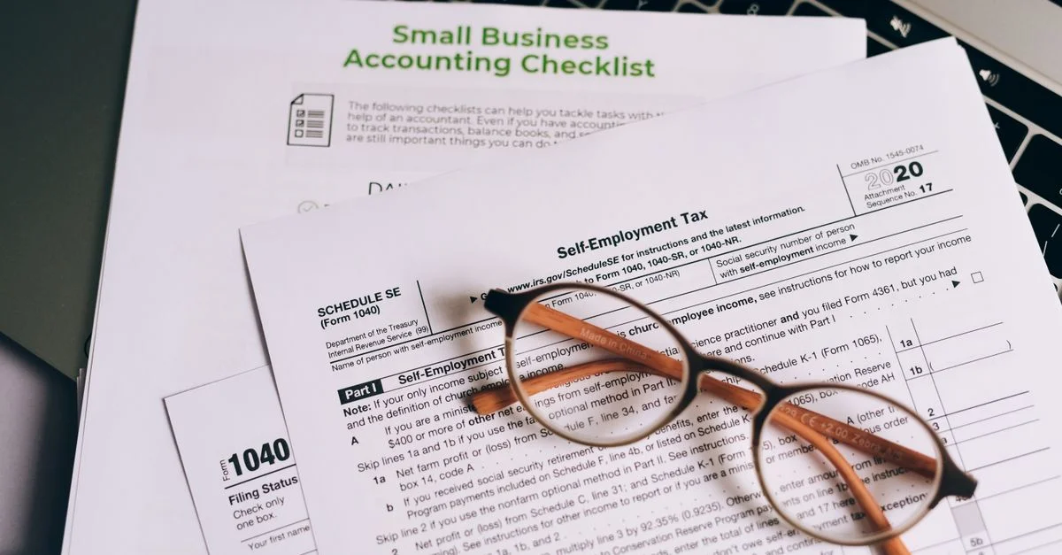 Gros plan sur des formulaires fiscaux et une liste de contrôle de comptabilité pour petites entreprises sur un ordinateur portable.
