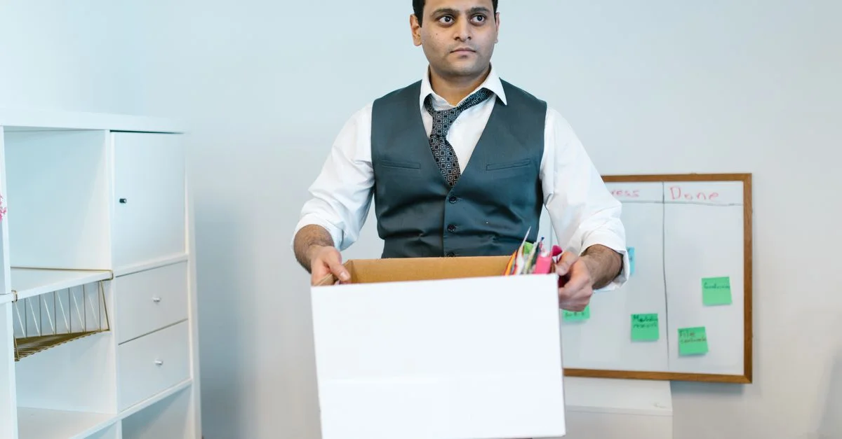 Homme professionnel organisant des affaires de bureau dans une boîte en carton, préparant une transition.