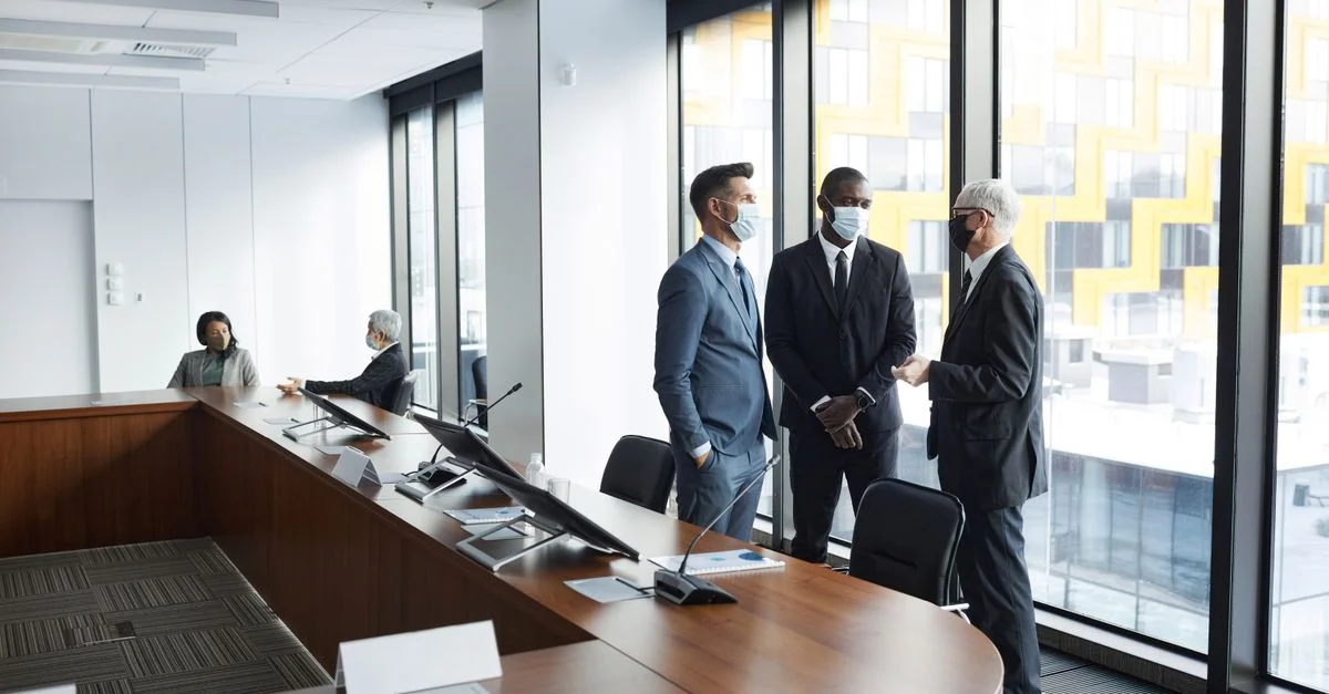Réunion d'affaires avec des professionnels portant des masques dans une salle de conférence moderne.